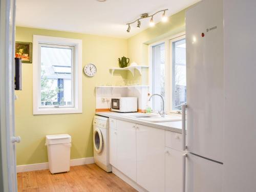 uma cozinha com um lavatório e uma máquina de lavar roupa em Puddingstone Cottage em Gartmore