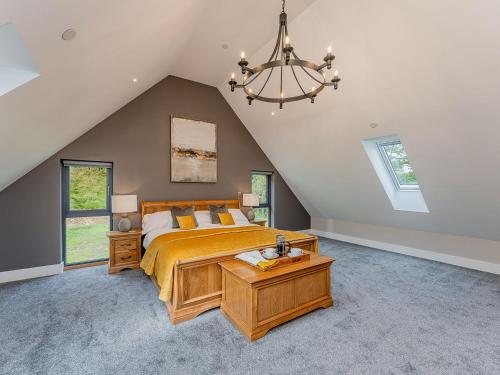 a bedroom with a large bed and a chandelier at Coed Y Pentre in Carno