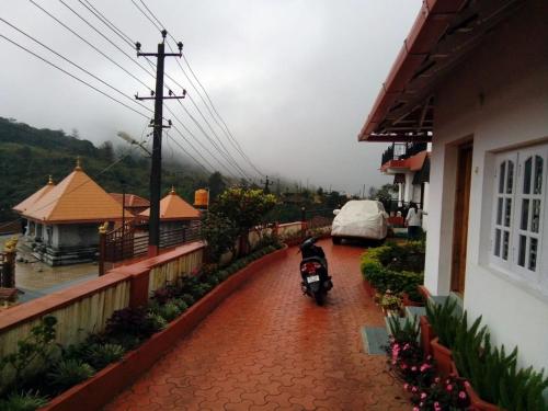 a motorcycle parked on a brick walkway next to a house at New Hill Valley Family Homestay-WiFi-View in Madikeri