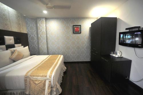 a hotel room with a bed and a tv at Hotel Lee International in Kolkata