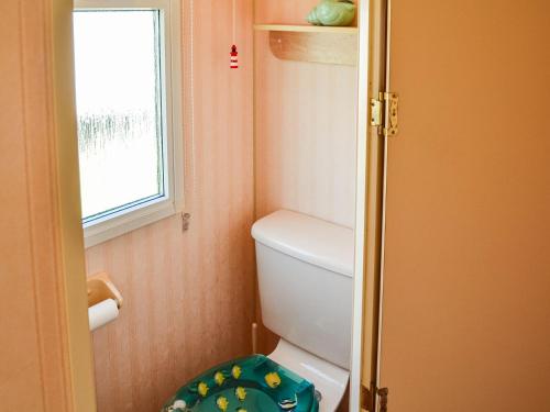 a small bathroom with a toilet and a window at Becleigh-daisy in Bacton