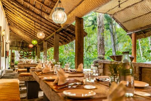 a restaurant with a long table in a forest at Amritara Shalimar Spice Garden Resort & Spa in Thekkady