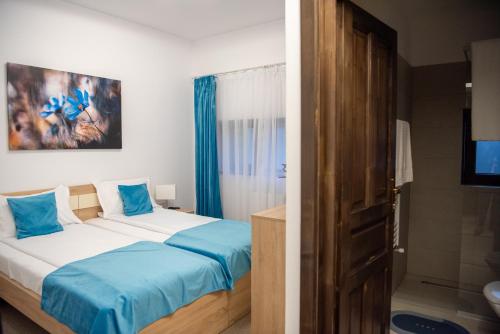 a bedroom with a bed with blue sheets and a bathroom at Pensiunea Black Mountain in Baia-Sprie