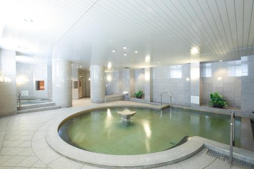 une grande piscine d'eau dans un bâtiment dans l'établissement HOTEL MYSTAYS PREMIER Sapporo Park, à Sapporo