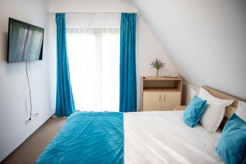 a bedroom with a bed with blue curtains and a television at Pensiunea Black Mountain in Baia-Sprie
