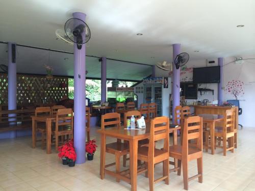 un comedor con mesas y sillas de madera y un restaurante en Ban Tai Resort, en Baan Tai