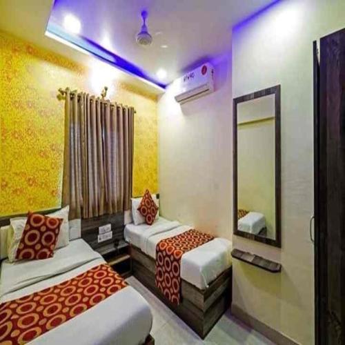 a hotel room with two beds and a mirror at Hotel New Sarah Inn, Andheri West in Mumbai