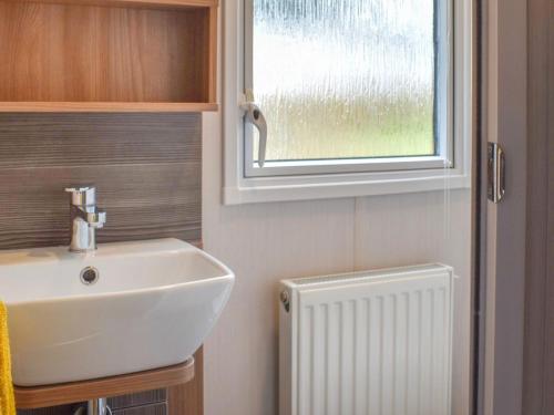 ein Badezimmer mit einem Waschbecken, einem Fenster und einem Heizkörper in der Unterkunft Little Bodieve in Wadebridge