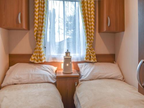 2 Betten in einem kleinen Zimmer mit Fenster in der Unterkunft Little Bodieve in Wadebridge