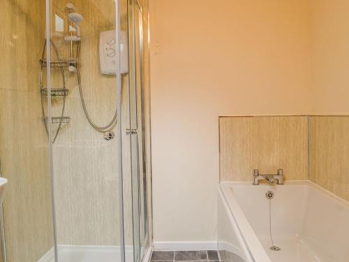 a bathroom with a shower and a bath tub at Owl Barn in Sidestrand