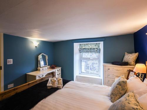 1 dormitorio con paredes azules, 1 cama y ventana en Glasfor, en Llwyngwril