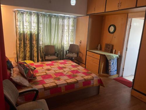 a bedroom with a bed and a kitchen with a window at Serene Living in Pune