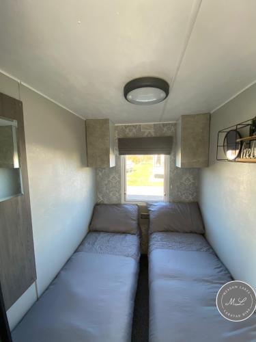 a small room with two beds in a trailer at Meadow Lakes 22 - Golden Palm, pet friendly, WiFi, bed linen - Meadow Lakes Caravan & Lodge Hire in Skegness