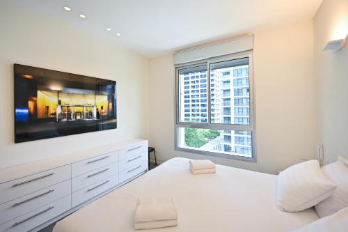 a white bedroom with a large flat screen tv at Mountain Vision by HolyGuest in Tel Aviv