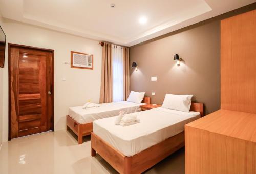 una habitación de hotel con 2 camas y una puerta en Josefina's Tourist Inn en Busuanga