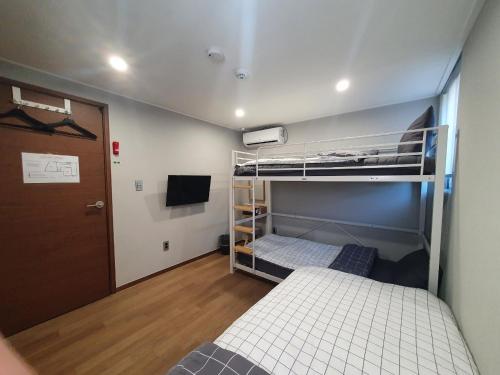 a small room with two bunk beds and a door at Hao Guesthouse in Hongdae in Seoul