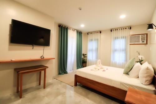 a bedroom with a bed and a flat screen tv at Josefina's Tourist Inn in Busuanga