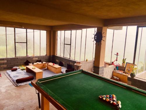 a room with a pool table in a room with windows at Dhauladhar Woodhouse in Malotha