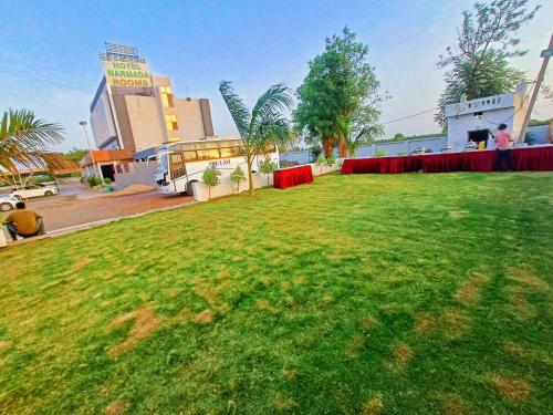 a large grassy field in front of a building at Hotel Narmada in Lāchharas