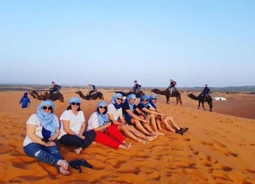 a group of women posing for a picture on the beach at Sunset Camp Merzouga in Merzouga