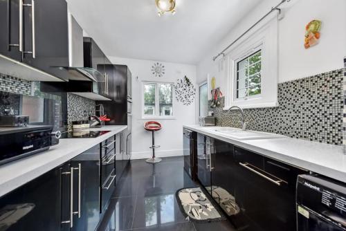 a kitchen with black and white cabinets and a sink at HAPPY HOURS HOME STAY in London