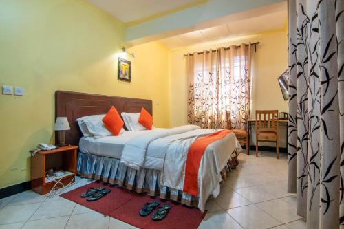 1 dormitorio con 1 cama grande con almohadas de color naranja en Crest Safari Lodge en Arusha
