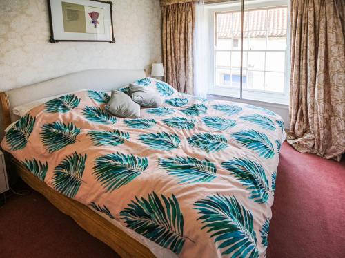 a bedroom with a bed with a tropical print at Peggs Yard in Aylsham