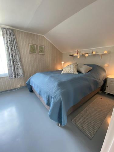 een slaapkamer met een blauw bed en een raam bij Unique and charming house at the foot of Lofoten's highest mountain in Svolvær