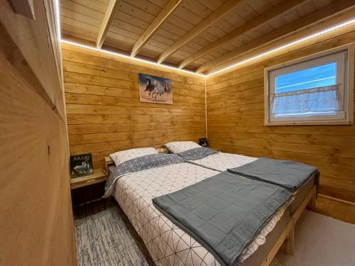 a bedroom with a bed in a wooden cabin at Domek wypoczynkowy - Stajnia Magenta 