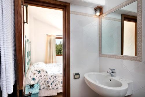 baño con lavabo, espejo y cama en Residenza Capriccioli en Porto Cervo