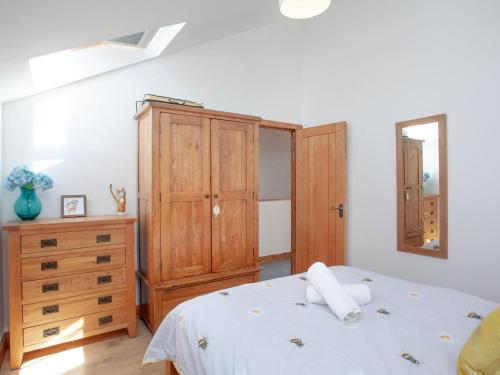 a bedroom with a bed and a wooden dresser at Old Highwood - Piglet Cottage in Luppitt