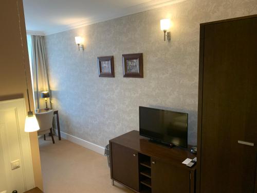 ein Hotelzimmer mit einem TV und einem Wohnzimmer in der Unterkunft Pension Eden in Želiezovce