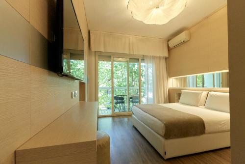 a bedroom with a bed and a large window at Hotel Saraceno Resort with Private Beach in Milano Marittima