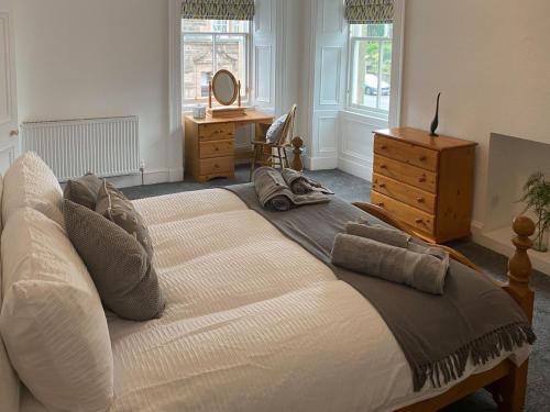 a bedroom with a large bed with a dresser and windows at Arden House in Comrie