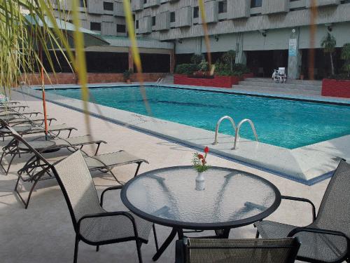 a pool with chairs, tables, chairs and umbrellas at Avari Lahore Hotel in Lahore