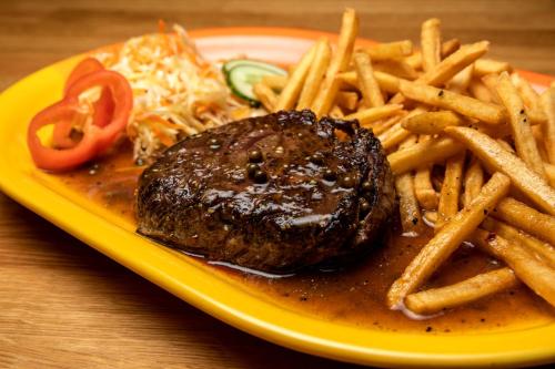 a plate of food with a steak and french fries at Penzion Lenka in Třemošná