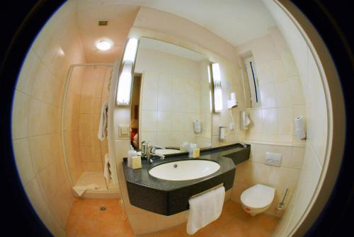 a bathroom with a sink and a toilet and a mirror at Hotel Lumen am Hauptbahnhof in Hamburg