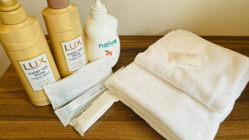 a table topped with bottles of lotion and a towel at Hostel Inn Hashimoto in Hashimoto
