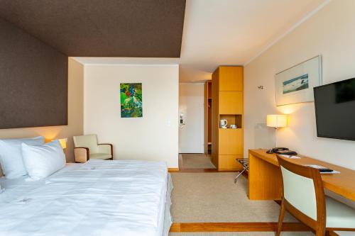 a bedroom with a bed and a desk and a computer at Seehotel Leoni in Berg am Starnberger See