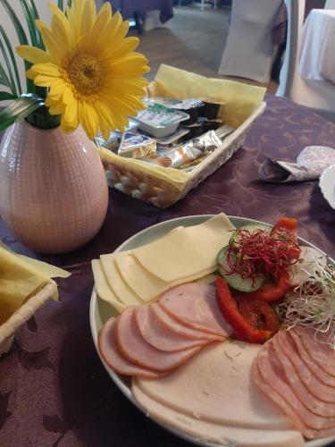 una mesa con un plato de comida y un jarrón con una flor en Hotel Olimpijski, en Tarnowskie Góry