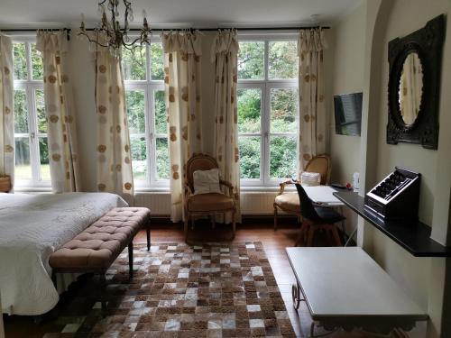 a bedroom with a bed and a desk and windows at Eremyten Hof in Evergem