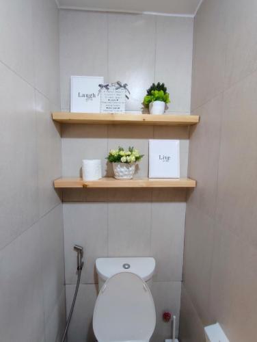 a bathroom with a toilet and shelves with plants at Cozy Studios at Inspiria Condo Davao City beside Abreeza Mall in Davao City