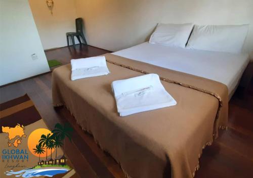 a bed with two white towels on top of it at GLOBAL IKHWAN RESORT in Kuah