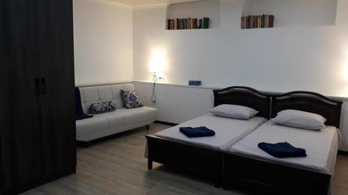 ein Schlafzimmer mit einem Bett mit blauen Kissen und einem Sofa in der Unterkunft Villa Mimi in Bazmakhpyur