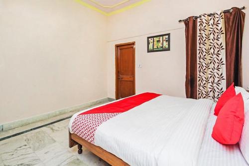 a bedroom with a bed with red pillows on it at Hotel Apoorva DLX in Jaipur