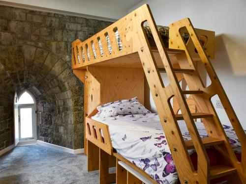 a bedroom with two bunk beds in a brick wall at Waterwynch in Criccieth