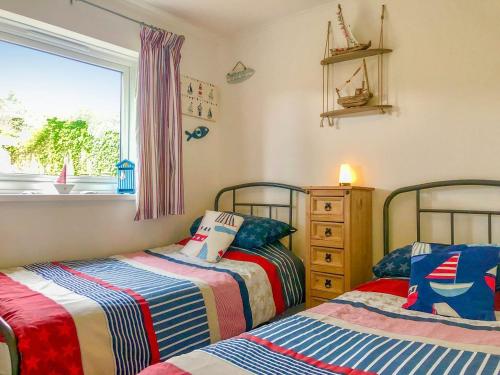 a bedroom with two beds and a window at The Captains Cabin in Brixham