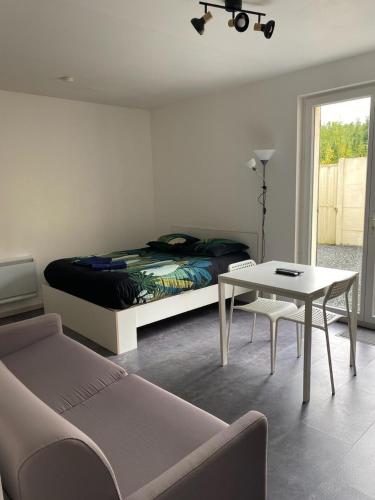 Studio le cosy centre de gaillon(wifi) في Gaillon: غرفة نوم بسرير وطاولة واريكة