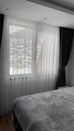a bedroom with a bed and a window with curtains at ORION APARTMENTS in Chepelare