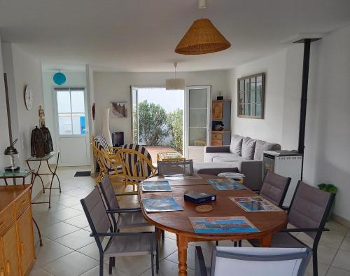 un salon avec une table et des chaises en bois dans l'établissement Maison de vacances Ile de noirmoutier, à LʼHerbaudière